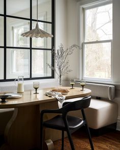 a dining room table with two chairs and a bench in front of the window,