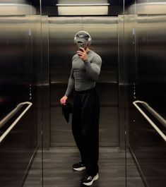 a man standing in front of an elevator taking a selfie with his cell phone