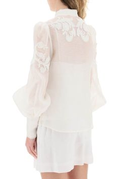 Zimmermann button-up blouse in linen silk organza, embellished with floral appliques and tonal beaded trimmings. Detailed with pearl-shaped buttons, it features a Mandarin collar, bouffant sleeves with long zip cuffs, and a removable jersey camisole with adjustable straps. The model is 177 cm tall and wears a size 1 Zimmermann. Size Info STANDARD Color Detail White Made In China Material 52%LI 48%SE Season One spring Season Two summer Product clothing Brand Zimmermann Size And Fit Elegant Summer Blouse With Embroidered Cuffs, Elegant Silk Tops With Embroidered Sleeves, Embroidered Long Sleeve Organza Blouse, Silk Blouse With Embroidered Long Sleeves, Elegant Fitted Tops With Embroidered Cuffs, Elegant Blouse With Embroidered Cuffs, Chic Silk Blouse With Floral Embroidery, Elegant Embroidered Bishop Sleeve Tops, Luxury Long Sleeve Embellished Blouse