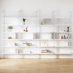 a white book shelf filled with books on top of a hard wood floor next to a wall