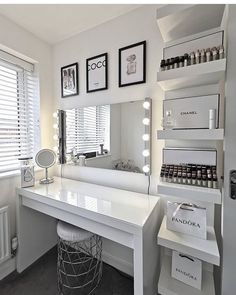 a white vanity with lots of lights on top of it and a mirror in the corner