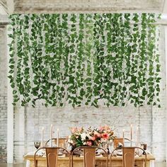 the table is set with candles and greenery hanging from it's ceiling above