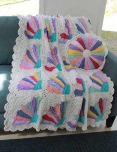 a crocheted blanket is sitting on a couch next to a blue chair and window