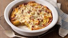 a casserole dish with meat and cheese in it on a cooling rack next to a fork