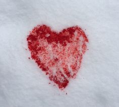 a heart - shaped piece of red powder is shown in the snow on a white surface