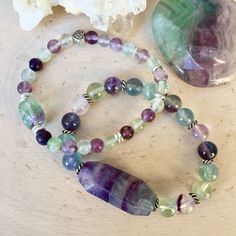 "These soothing Fluorite Beaded Bracelets are so fun! The gorgeous natural stone beads vary in colors including greens, purples and blues. The bracelets have silver plated accent beads including one with a heart. You have a choice of two stretch bracelets: #1 Medium Center Bead Bracelet - 6mm round beads with a 13-14mm pebble center bead and one Celtic heart bead. #2 Large Center Bead Bracelet - 8mm round beads with a 33mm x 14mm faceted oval center bead. Both styles are very pretty and unique. Multicolor Amethyst Bohemian Bracelets, Bohemian Multicolor Amethyst Beaded Bracelets, Multicolor Amethyst Beaded Bracelets With Natural Stones, Multicolor Amethyst Gemstone Beaded Bracelets, Multicolor Amethyst Natural Stones Bracelet, Multicolor Amethyst Crystal Necklaces For Healing, Fluorite Bracelet, Chalcedony Bracelet, Celtic Heart