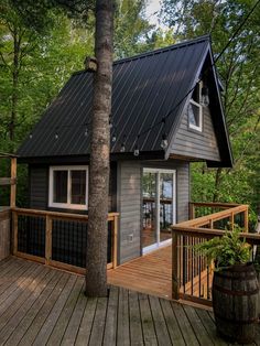 a small cabin in the woods with a deck and railings on it's side