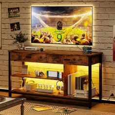 a man standing in front of a tv on top of a wooden table next to a brick wall