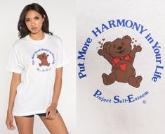 "Vintage 90s t shirt in white with a Bear graphic and \"Put More Harmony in your Life\" and \"Project Self Esteem\" on the front. Please see measurements and condition below. Every garment we sell is authentic vintage and one-of-a-kind! You will receive the exact item photographed. Condition: Very good vintage. Best fits women's: Labelled Large, but runs modern medium  Tag: Screen Stars Material:  Cotton Polyester MEASUREMENTS Taken from seam to seam while the garment is lying flat. Double the a 90s Shirts Graphic Tees, Teddy Bear T Shirt, Teddy Bear Shirt, Blue Shift Dress, Vintage Pullovers, 90s Shirts, Bear Graphic, Bear Shirt, Bell Bottom Pants