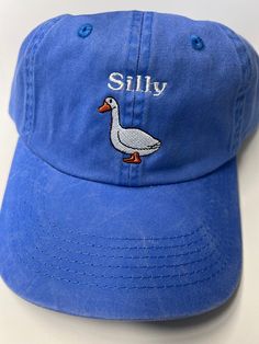 Looking for a fun and quirky accessory to add to your everyday look? Look no further than the None Silly Goose Dad Hat! Crafted from high-quality materials by trusted maker Port Authority, this washed blue hat is the perfect way to add a touch of humor to your outfit. The hat's playful design features a silly goose graphic front and center, adding an element of lighthearted fun that's sure to turn heads. With its comfortable fit and adjustable strap, this Dad Hat is perfect for any casual occasi Cheap Fun Blue Hats, Blue Washed Hat With Curved Brim, Trendy Brimmed Cotton Baseball Cap, Cotton Brimmed Trucker Hat For Summer, Summer Cotton Brimmed Trucker Hat, Summer Brimmed Cotton Trucker Hat, Denim Blue Hat With Curved Brim, Trendy Washed Baseball Cap, Vintage Soft-washed Hat, One Size Fits Most