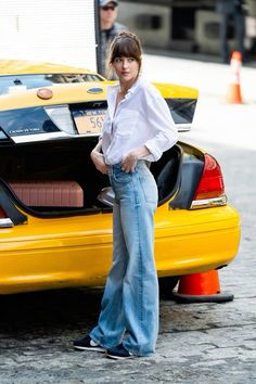 a woman standing next to a yellow taxi