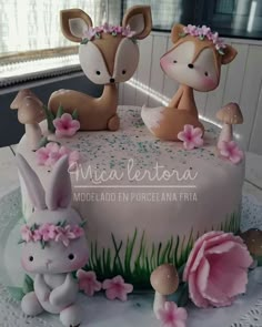 the cake is decorated with pink flowers and two little deer figurines on top