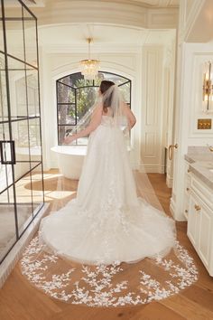 a woman in a wedding dress is walking down the hall with her veil over her head