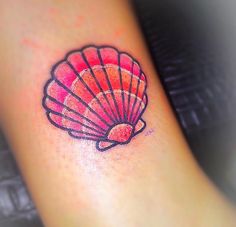 a small pink shell tattoo on the ankle is shown in red and black ink,