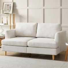 a white couch sitting in a living room next to a table and lamp on top of a rug