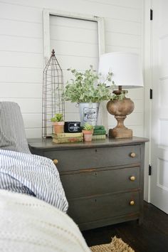 a bedroom with a bed, nightstand and lamp on it's side table in front of the door