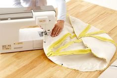 a woman is using a sewing machine to sew something on the floor with her hands