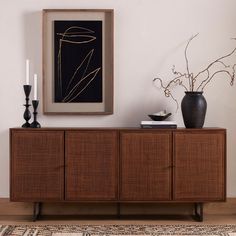 a brown sideboard with two vases on it and a painting hanging above it