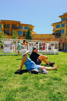 two people sitting on the grass in front of a building