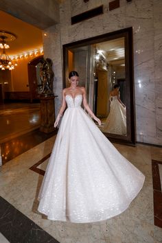 a woman in a white wedding dress standing in front of a mirror