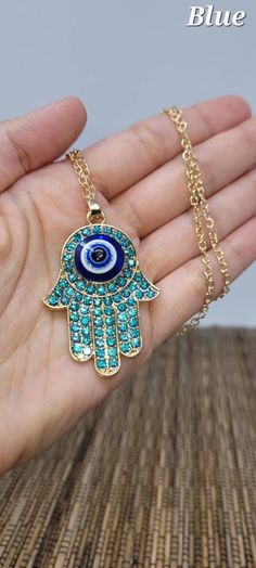 "Hamsa Hand of Fatima Necklace. This beautiful Necklaces is Gold-tone, the Pendant have a blue eye of protection in the center and rhinestones. Hand of Fatima and Blue eye of protection: Protective against evil and Brings Good Luck. Necklace Adjustable from 16\" Inches up to 18\" Inches Around the Neck\" Inches around the neck Pendant is 1.5\" Inches Long FAST & FREE SHIPPING! *First Class Mail* Visit my Etsy Shop to see more Designs! Handmade Hamsa Hand Earrings, Hamsa Necklaces, Hamsa Bracelet Blue Crystal Pendant Necklace With Adjustable Chain, Blue Long Necklace With Adjustable Chain, Blue Costume Jewelry Necklaces With Lobster Clasp, Blue Charm Necklace With Adjustable Chain, Adjustable Blue Charm Necklace With Lobster Clasp, Blue Long Necklace Suitable As A Gift, Blue Pendant Charm Necklaces For Spiritual Style, Handmade Light Blue Spiritual Necklaces, Blue Pendant Necklace With Lobster Clasp