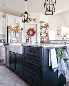 a kitchen with white cabinets and black island in the center is decorated with autumn decorations