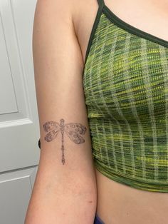 a woman with a dragonfly tattoo on her left arm and right arm behind her back