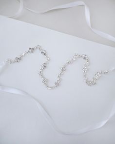 Dainty series of rhinestones attached in white satin ribbon gives a delicate and elegant touch to your hair do. Perfect for wedding, brides and bridesmaids, holiday party, casual wear, and any special occasions. DETAILS:COLOR: SILVERLENGTH: 0.5"WIDTH: 17"ASSEMBLED IN USAIMPORTED MATERIALS Adjustable Bridal Accessories With Rhinestones, Adjustable Rhinestone Bridal Accessories, Elegant White Sashes With Rhinestones, Elegant Bridal Belt With Satin Bow For Wedding, White Crystal Bridal Belt For Party, Adjustable Rhinestone Bridal Accessories For Wedding, Elegant Bridal Belt With Satin Bow For Bridesmaid, Silver Bridesmaid Sashes Bridal Accessories, Elegant White Bridal Belt With Satin Bow