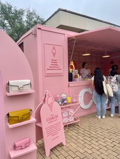 people are standing in front of a pink ice cream stand that is shaped like an ice cream cart