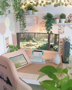 a desk with a computer monitor and keyboard on it, surrounded by potted plants