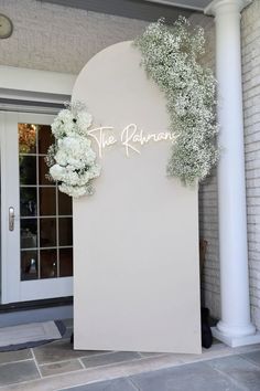 a white sign that says the palace with flowers on it in front of a building