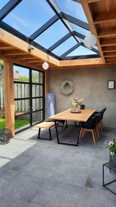 an outdoor dining area with glass roof and wooden table