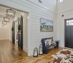 a living room with wood floors and white walls, along with an entryway leading to the front door