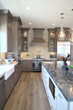 a large kitchen with wooden floors and stainless steel appliances, along with marble counter tops