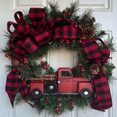 a christmas wreath with a red truck and pine cones