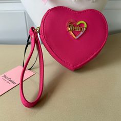 The Juicy Couture Pink Flash Love Mode Heart Zip Around Wristlet Is An Essential Accessory For Every Woman. This Designer Piece Is Limited Edition And Has A Heart Shape Adorned With Vibrant Multicolor Rhinestones. The Wristlet Is Made Of High-Quality Faux Leather, Ensuring Its Durability To Keep Your Belongings Safe And Secure. It Comes With A Wrist Strap In A Beautiful Pink Color, Making It Perfect For Any Occasion. The Zip Closure Ensures Easy Access And Organization Of Your Essentials. Please Pink Heart-shaped Wallets For Gifts, Trendy Wristlet With Zipper Closure For Gift, Trendy Wristlet With Zipper Closure As Gift, Pink Heart-shaped Wallet For Gift, Heart-shaped Pink Wallet As Gift, Pink Heart-shaped Wallets For Valentine's Day, Trendy Wallets For Valentine's Day Gift, Trendy Wallets As Valentine's Day Gifts, Color Making