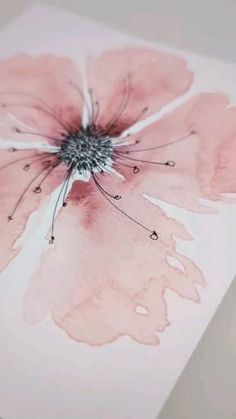 a close up of a pink flower on a piece of paper with watercolor paint