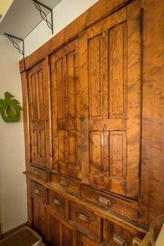 an old wooden armoire sitting in a room next to a green clock on the wall