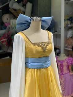 a yellow and blue dress on display in a room with other clothing items behind it