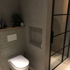 a white toilet sitting in a bathroom next to a walk - in shower and tiled walls