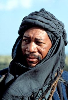 a man with dreadlocks on his head and scarf around his neck looking at the camera