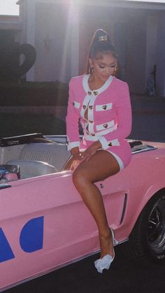 a woman sitting on top of a pink car