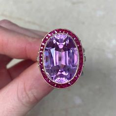 This impressive gemstone ring features a natural 24.10-carat oval-cut kunzite with excellent pink color saturation. Surrounding the center kunzite is a halo of French-cut rubies. The under-gallery is decorated with a lace design and diamonds. This ring is made in 18k yellow gold.
The total approximate ruby weight is 1.20 carats. The total approximate diamond weight is 0.50 carats.
The measurements, including the ruby halo, are 19mm x 25mm.
This ring can be resized to any finger size at no extra Luxury Amethyst Ring With Oval Cabochon, Luxury Kunzite Ring For Formal Occasions, Luxury Hallmarked Oval Cabochon Amethyst Ring, Estate Diamond Jewelry, French Cut, Halo Ring, Halo Rings, Lace Design, Amethyst Ring