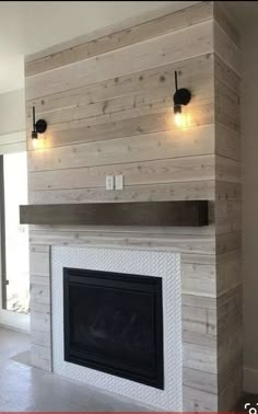 an empty living room with a fireplace and two lights on the side of the wall