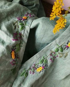 a close up of a green cloth with flowers on it and yellow flowers in the background