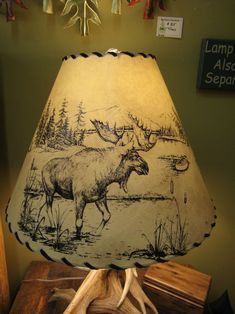 a lamp shade with an image of a moose and elk on it in front of a green wall