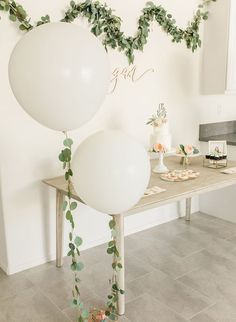 white balloons and greenery on a table