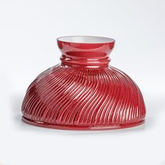 a red glass vase sitting on top of a white table