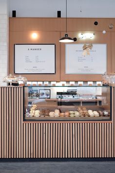 a bakery counter with two menus on the wall and food in front of it