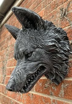 a statue of a dog on the side of a brick building with it's mouth open